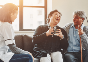 OT carering for 2 elderly people, man and woman talking and laughing over tea