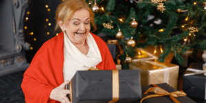 Elderly Woman Opening Chrismtas Presents Beside the Christmas Tree