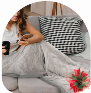 Woman drinking coffee on her phone under an electric heated blanket