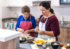 Daughgter help her elderly mother prepare dinner in the kitchen