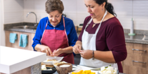 Daughgter help her elderly mother prepare dinner in the kitchen