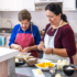 Daughgter help her elderly mother prepare dinner in the kitchen