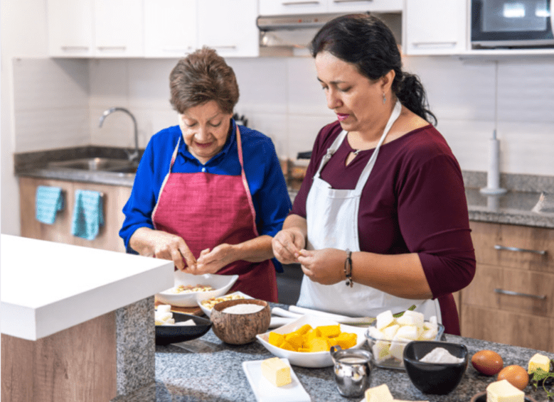 Daughgter help her elderly mother prepare dinner in the kitchen