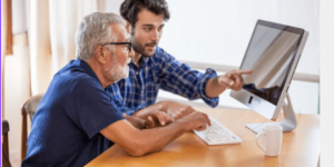 Adult Son showing his elderly father how to use the computer