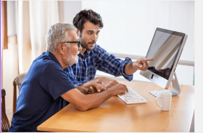 Adult Son showing his elderly father how to use the computer