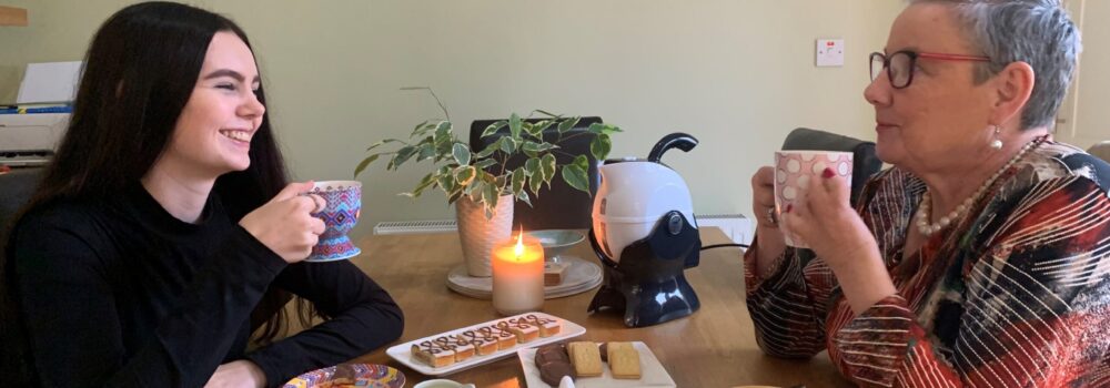 Grandmother and Granddaughter having a cup of tea and biscuits together