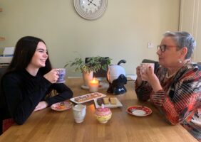 Grandmother and Granddaughter having a cup of tea and biscuits together