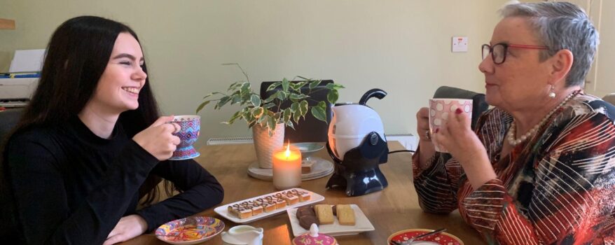 Grandmother and Granddaughter having a cup of tea and biscuits together